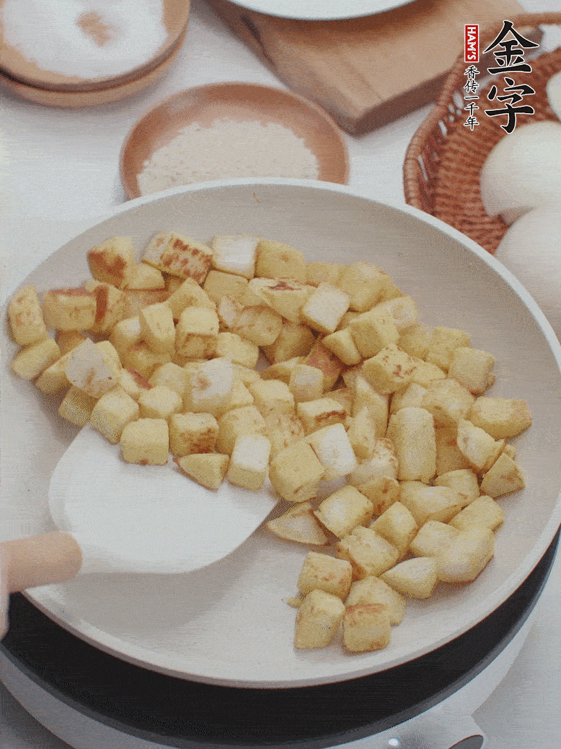 起鍋熱油，倒入饅頭丁，小火煎至蛋液凝固定型再翻面，饅頭丁部煎至金黃時(shí)盛起待用。